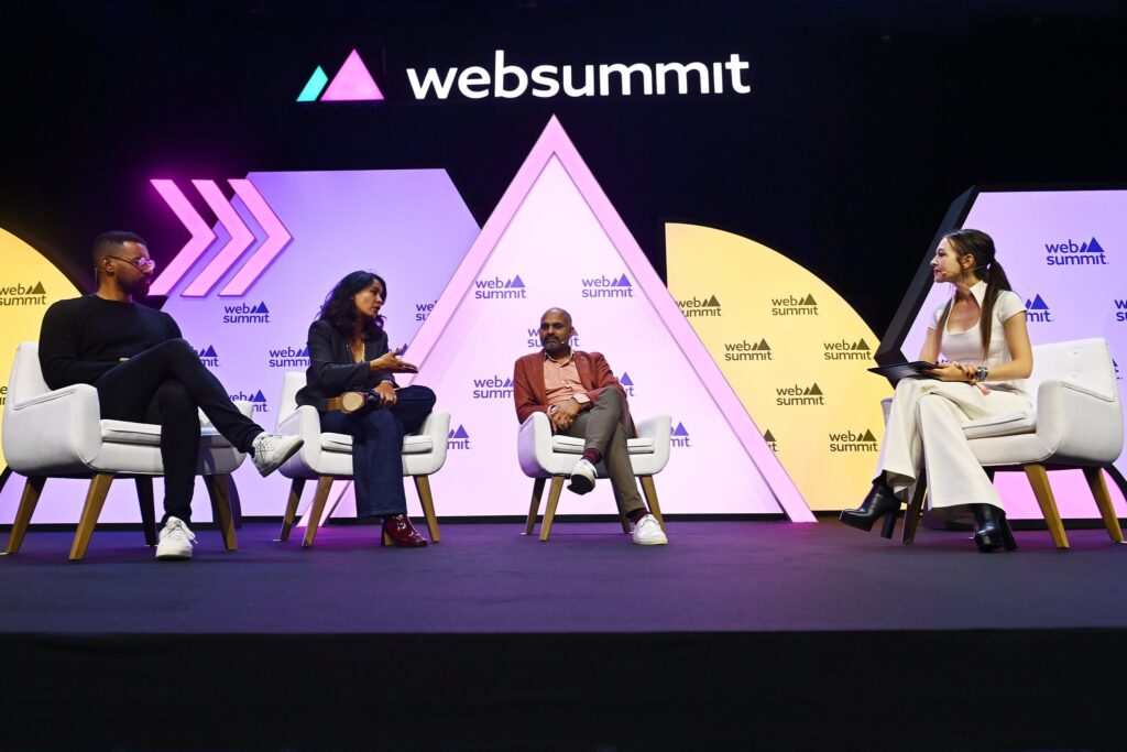 Four people (from left, Fiat Ventures general partner Drew Glover; France Digitale managing director Maya Noël; Zopa CEO Jaidev Janardana; Xinhua News Agency business correspondent Martina Fuchs) sit in armchairs. They are all wearing headset mics and have their legs crossed. One of the people (Maya Noël) is gesturing with their right hand, and appears to be speaking. This is the MoneyConf stage during Day 1 of Web Summit 2023 at the Altice Arena in Lisbon, Portugal.