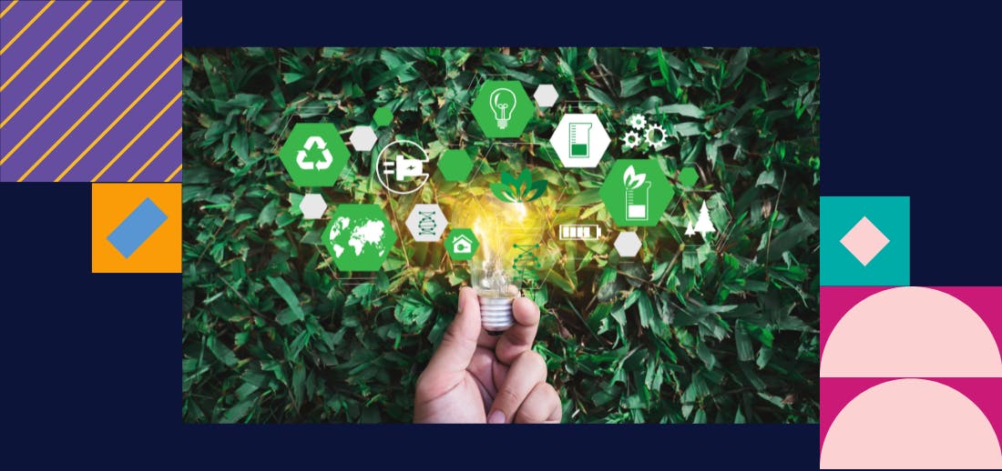 Hand holding bulb surrounded by green vector images against backdrop of green hedge