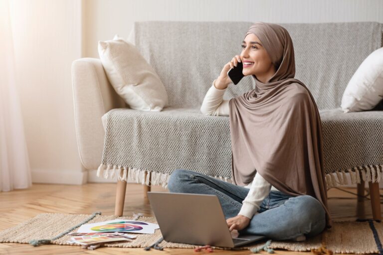 Remote worker sits on the floor with laptop, talking on the phone